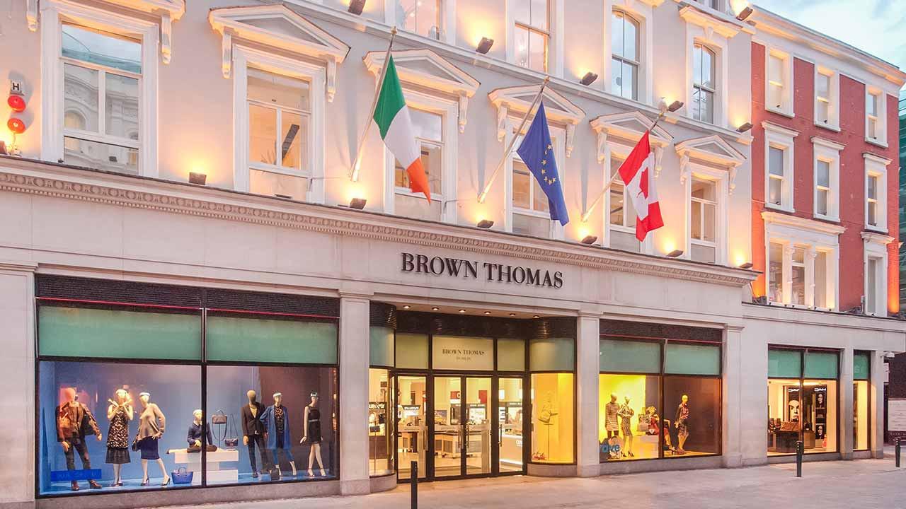 Elegant storefront of Brown Thomas with mannequins in the window display and flags above.