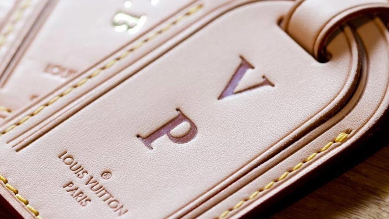 Close-up of a leather Louis Vuitton luggage tag with embossed initials 'VP.'


